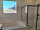 Luxurious bathroom with soaking tub, glass-enclosed shower, and bright window at 17586 W Blue Sky Dr, Surprise, AZ 85387