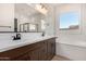 Bright bathroom featuring double vanity, soaking tub, large window, and tiled walls at 17586 W Blue Sky Dr, Surprise, AZ 85387