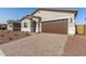 Charming single-Gathering home featuring a brick driveway, a two-car garage, and a well-manicured front yard at 17586 W Blue Sky Dr, Surprise, AZ 85387