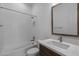 Bright bathroom features a shower-tub, white tile surround, and modern vanity with wood accents at 21627 W Mariposa St, Buckeye, AZ 85396