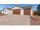 View of the home's two-car garage with a brick driveway at 17868 W Blue Sky Dr, Surprise, AZ 85387