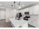 Modern kitchen with stainless steel appliances, white cabinetry, island sink, and elegant pendant lights at 17868 W Blue Sky Dr, Surprise, AZ 85387