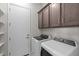 Laundry room with modern washer and dryer beneath stained cabinets at 19341 W San Juan Ave, Litchfield Park, AZ 85340