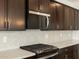 Close up view of a kitchen featuring stainless steel appliances, white countertop, and dark wood cabinets at 17703 W Southgate Ave, Goodyear, AZ 85338
