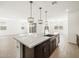 Kitchen island with stainless steel sink, dark wood cabinets and white countertop, and pendant lighting at 17703 W Southgate Ave, Goodyear, AZ 85338