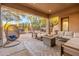 Inviting covered patio featuring a fire pit, comfortable seating, and views of a landscaped backyard with a water fountain at 32427 N 71St Way, Scottsdale, AZ 85266