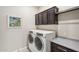 Laundry room with washer, dryer, and dark brown cabinets at 13199 W Baker Dr, Peoria, AZ 85383