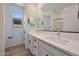 Bright bathroom featuring double sinks, white cabinets, and wood-look tile flooring at 17316 W Via Dona Rd, Surprise, AZ 85387