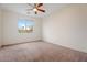 This vacant bedroom features neutral carpet, a ceiling fan, and a window with a view at 5531 W Gwen St, Laveen, AZ 85339