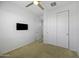 Bright, carpeted bedroom with ceiling fan, closet with sliding doors, and a wall-mounted television at 40015 W Crane Dr, Maricopa, AZ 85138