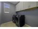The Laundry Room features modern washer and dryer units and convenient overhead storage at 40015 W Crane Dr, Maricopa, AZ 85138