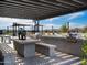 Outdoor kitchen and dining area with built-in grill, counter seating, and pergola at 3339 E Audrey Dr, San Tan Valley, AZ 85143