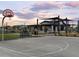 Community basketball court with benches, landscaping, shade umbrellas, and the community clubhouse in the background at 3375 E Audrey Dr, San Tan Valley, AZ 85143