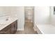 Bright bathroom with dual vanity, wood-look tile floor, and a view of a soaking tub and closet at 17666 W Pierson St, Goodyear, AZ 85395