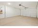 Spacious garage with a roll-up door, concrete floor, and white walls at 37028 W Prado St, Maricopa, AZ 85138