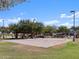 Outdoor sand volleyball court with mature shade trees, and lush grass surrounds the area, creating the perfect backdrop for a friendly game at 37028 W Prado St, Maricopa, AZ 85138