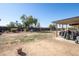 Backyard features fence line, mature trees, storage for firewood, a grill, and covered patio area at 3740 E Edna Ave, Phoenix, AZ 85032