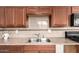 Traditional kitchen featuring wood cabinets, a stainless steel sink, and tile backsplash at 6414 W Osborn Rd, Phoenix, AZ 85033