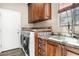 Bright laundry room with granite counters, wood cabinets, and a utility sink at 34704 N 93Rd Pl, Scottsdale, AZ 85262