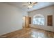 Spacious bedroom with wood flooring, ceiling fan, an arched window, and walk-in closet at 37615 N Tranquil Trl, Carefree, AZ 85377