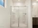 Bathroom featuring a glass-enclosed shower with shelving and a white shower surround at 8657 W Warner St, Tolleson, AZ 85353