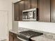 Shows new stainless steel microwave and gas range atop granite counter on dark wood cabinets at 8657 W Warner St, Tolleson, AZ 85353