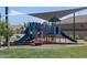 Shaded community playground with slides, climbing structures, and a grass lawn in view at 8657 W Warner St, Tolleson, AZ 85353