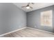 Cozy bedroom with gray walls, wood-look floors, and a ceiling fan at 15936 W Latham St, Goodyear, AZ 85338