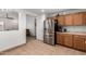 Kitchen featuring stainless steel refrigerator and wood cabinets, adjacent to living area at 2083 S 155Th Ln, Goodyear, AZ 85338
