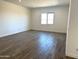 Bright living room with wood-look floors, a large window, and neutral paint at 43513 N Wollemi St, Queen Creek, AZ 85140
