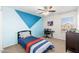 A cozy bedroom painted with two shades of blue, ceiling fan, work desk, and dark furnishings at 4660 E Torrey Pines Ln, Chandler, AZ 85249