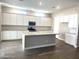 Modern kitchen boasts white cabinets, a center island with a sink, and stainless steel appliances at 43429 N Wollemi St, Queen Creek, AZ 85140