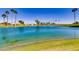 Scenic lake view on the golf course with reflections of palm trees and a clear blue sky at 3721 N 150Th Ct, Goodyear, AZ 85395