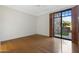 An empty bedroom with glossy wood floors and a sliding glass door to an outdoor patio at 2 E Biltmore Estates Dr # 115, Phoenix, AZ 85016