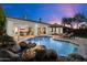 Backyard pool featuring a rock waterfall, lounge chairs, and covered patio area perfect for outdoor entertaining at 744 E County Down Dr, Chandler, AZ 85249