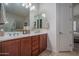 Bathroom featuring double sinks, framed mirrors, vanity lighting, wood cabinetry, and tile floors at 15312 S 181St Dr, Goodyear, AZ 85338
