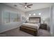 Neutral Primary bedroom featuring a ceiling fan, large window, and a king-size bed with decorative pillows at 15312 S 181St Dr, Goodyear, AZ 85338