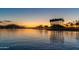 Scenic lake view at sunset with palm trees and distant city lights at 15312 S 181St Dr, Goodyear, AZ 85338