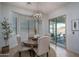 Cozy dining area with a round table, upholstered chairs, view to a pool, and a modern chandelier at 15312 S 181St Dr, Goodyear, AZ 85338