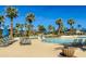 Gathering-friendly community pool featuring sun loungers and umbrellas surrounded by lush palm trees and pristine blue sky at 2135 N Heritage St, Buckeye, AZ 85396