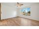 This bedroom has a ceiling fan, hardwood floors, white walls, and a large window overlooking a fenced yard at 29007 N 120Th Dr, Peoria, AZ 85383