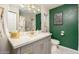 Modern bathroom features a gray vanity with gold fixtures, complemented by green accent walls and marble flooring at 602 E Taylor St, Tempe, AZ 85288