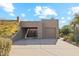 Tan stucco exterior, two-car garage, and desert landscaping at 9250 E Whitethorn Cir, Scottsdale, AZ 85266