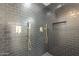 Close-up of a shower with dark tile, gold fixtures, and a built-in shelf at 1323 W Tuckey Ln, Phoenix, AZ 85013