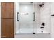 Clean bathroom showcasing a shower and tub with glass door and wooden storage at 1345 W Edgemont Ave, Phoenix, AZ 85007