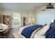 Bright main bedroom featuring an ensuite bathroom, light wood floors, a ceiling fan, and ample closet space at 14426 W Morning Star Trl, Surprise, AZ 85374