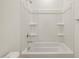 Close-up of a bathtub-shower combo with white enclosure and shelves, complemented by a white toilet at 16023 W Desert Hollow Dr, Surprise, AZ 85387