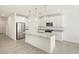 Bright kitchen features white cabinets, stainless steel appliances, granite counters and a center island with pendant lighting at 16023 W Desert Hollow Dr, Surprise, AZ 85387