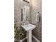 Stylish powder room featuring a pedestal sink, decorative mirror, and modern wallpaper at 2835 E Los Gatos Dr, Phoenix, AZ 85050