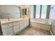 Bright bathroom with dual vanities, large mirror, and a soaking tub by a window at 13613 W Cypress St, Goodyear, AZ 85395